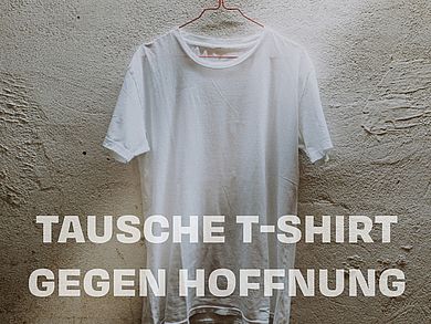 T-Shirt hängt auf einem Kleiderbügel an der Wand