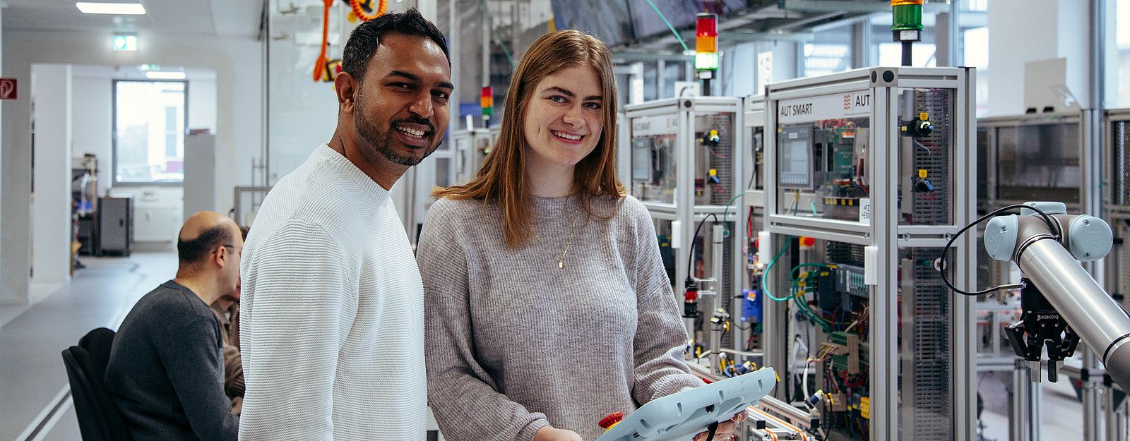 Two students program a robot in the digital factory.