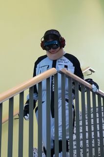 Eine Schülerinm geht in einem Anzug mit Brille und Kopfhörern eine Treppe hinunter