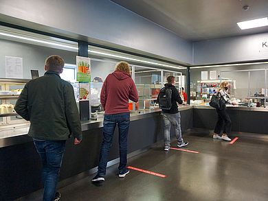 Studierende stehen mit Abstand vor der Essensausgabe