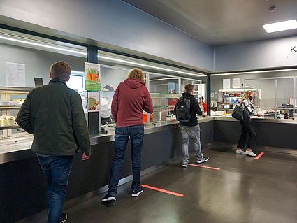 Studierende stehen mit Abstand vor der Essensausgabe