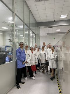 Gruppenbild in einer Fabrik, alle tragen Kittel und Haarnetze