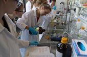 Studentin füllt Flüssigkeit aus einer großen, braunen Flasche in einen Messbecher im Labor Verfahrenstechnik