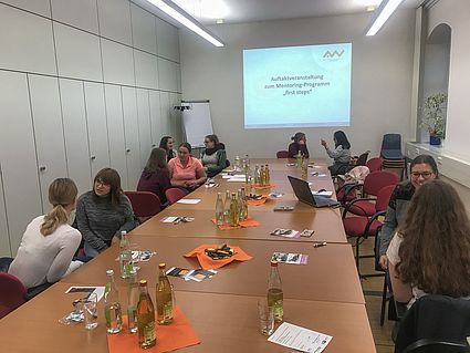 Studentinnen sitzen im Zweiergespräch um einen großen Tisch