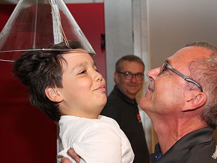 Kinder mit Kopf unter Glashaube, aus der Luft strömt