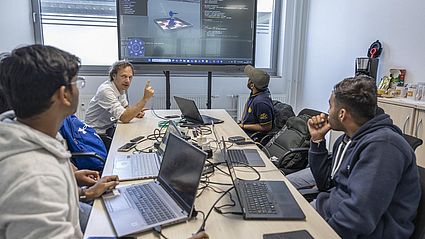 Studierende sitzen an Laptops