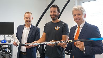 Drei Männer halten einen Eishockeyschläger