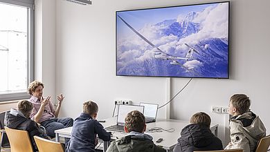 Schüler siten in einer Gruppe sehen ein Flugzeug auf deBildschirm