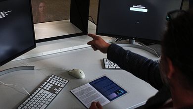 Person vor Computer und Hologramm im Hintergrund