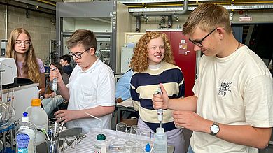 Schülerinnen und Schüler mit Pipette in der Hand