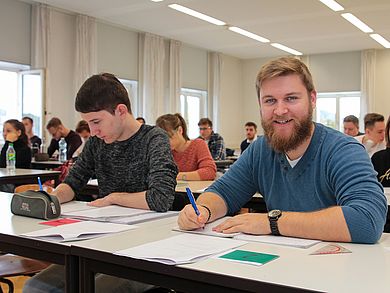 Tobias Faderl sitzt an einem Tisch im Hörsaal und rechnet 