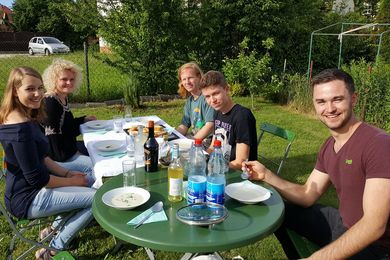Sechs Menschen um Tisch im Garten