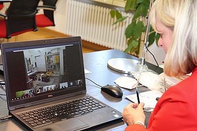 Präsidentin der Hochschule sitzt vor ihrem Computer und auf dem Bildschirm sind die Beteiligten zu sehen
