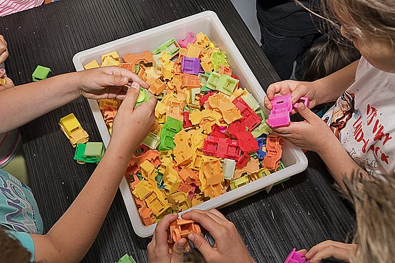 Schülerinnen und Schüler bauen kleine, bunte Spielzeugautos zusammen