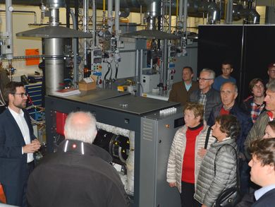 Besucher stehen im Komptenezzentrum Kraft-Wärme-Kopplung und Raphael Lechner erklärt