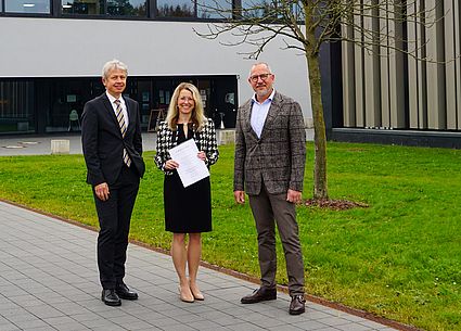 Drei Personen mit Urkunde