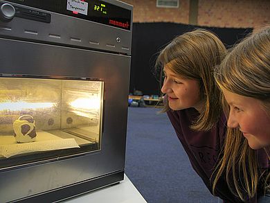 Zwei Mädchen schauen in die Vakuumkammer