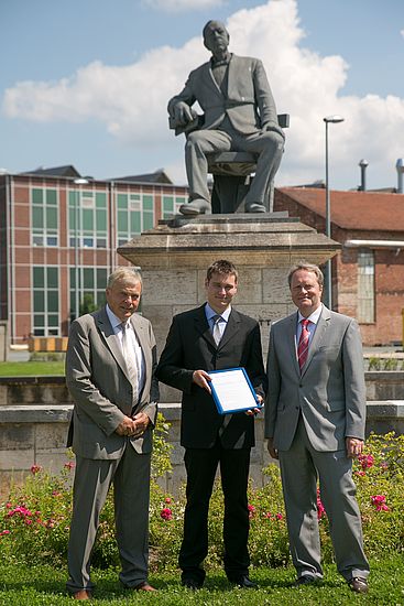 (v.l.n.r.) Dipl.-Ing. V. Thomas (VDI), Preisträger  Dipl.-Ing. (FH) J. Hauer (DEPRAG) und Dr. U. Dilling (MAN) vor dem Denkmal des Gründers Theodor Freiherr von Cramer-Klett im Werksgelände der MAN/Nürnberg