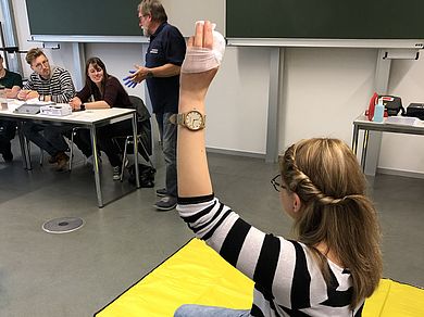 Studentin hält verbundenen Finger nach oben