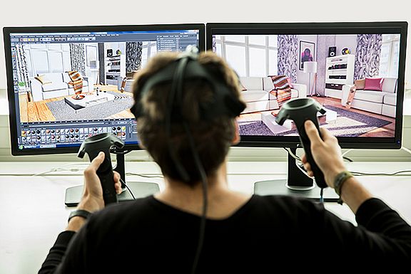 Studentin mit Controllern vor zwei Bildschirmen