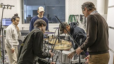Studierende am Schlagzeug stellen Mikrofone auf