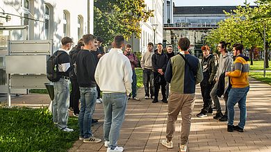 Gruppe vor Gebäude auf dem Campus