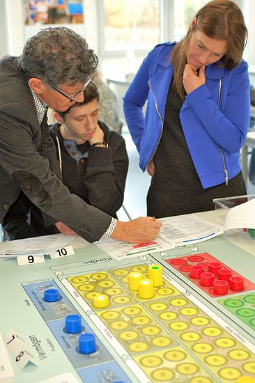 Die Spielleiter Prof. Duttle und Prof. Heigl helfen bei der „Buchführung“.