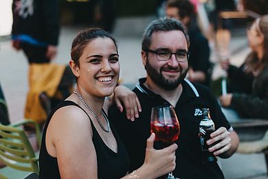 Zwei Personen stoßen mit Wein und Bier an