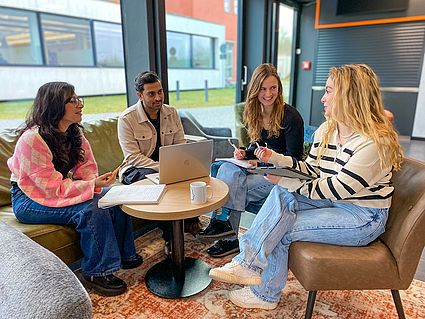 Studierende sitzen um einen Tisch 