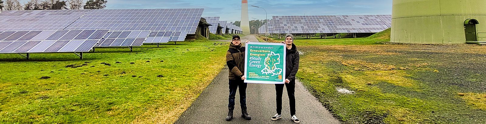 Two students stand in front of a wind farm