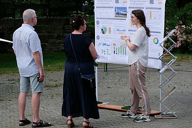 Menschen informieren sich an einem Infostand mit Infografiken