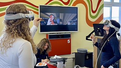 Teamwork in der Kleingruppe: Zwei Schülerinnen mit Apple Vision Pro navigieren durch Knochen und Knorpelstrukturen des Brustkorbs, während ihre Mitschülerinnen die Aufgaben auf dem Arbeitsblatt festhalten.
