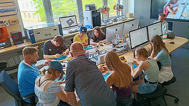Besucher um Tisch im MakerSpace