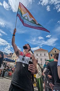 Eine Person schwenkt eine Regenbogenfahne