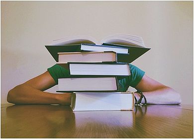 Student hinter Bücherberg
