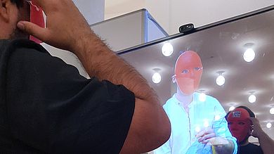 Mann mit Maske steht vor Bildschirm