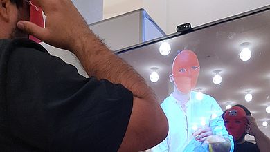 Mann mit Maske steht vor Bildschirm