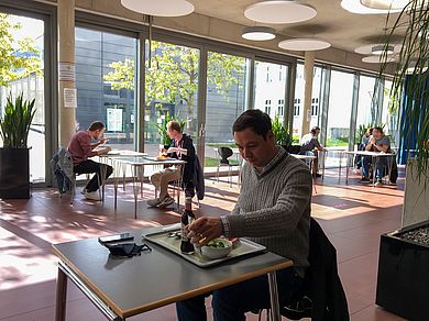 Menschen sitzen mit Abstand beim Essen