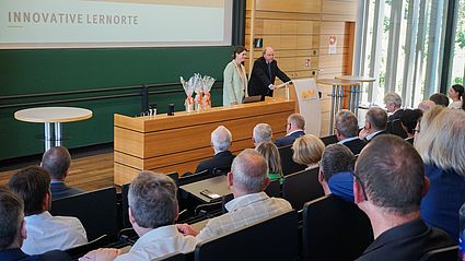 Prof. Dr. Wolfgang Weber, Vizepräsident der OTH Amberg-Weiden, blickt beim 10-jährigen Jubiläum gemeinsam mit Projektmitarbeiterin Hanna Gallitzendörfer und zahlreichen geladenen Gästen auf die Erfolgsgeschichte der Innovativen LernOrte an der Hochschule