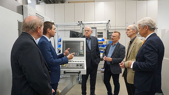 Eine Gruppe Männer steht neben einer Maschine