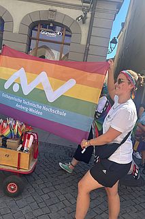 Eine Person hält eine Regenbogenfahne