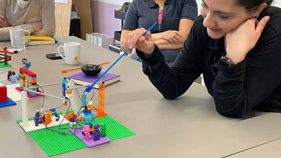 Maria Pusoma (rechts im Bild) zeigt auf ihr individuelles Legomodell, das sie während ihrer Faciliator-Ausbildung in Hannover gebaut hat.