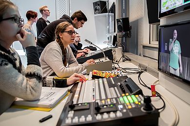 Studierende sitzen in der Regie an Bildmischer und Audiomischer