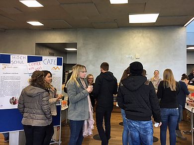 Besucherinnen und Besucher beim Gedankenaustausch im HochschulCafé