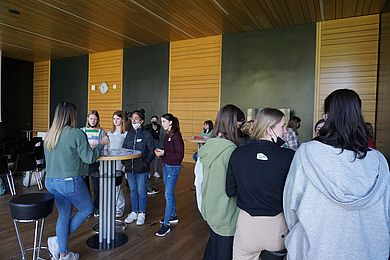 Schülerinnen und Studentinnen unterhalten sich an Stehtischen