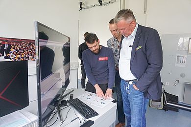 Christopher Fleischmann und Prof. Dr. Christian Schmidkonz zeigen Christian Engel seine Ergebnisse