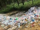 Plastikflaschen liegen in Massen im Wald 