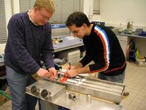 Studenten beim Einpassen von jeweils drei Metallhydrid-Einzelspeichern in ein Tanksystem für ein Brennstoffzellenfahrzeug