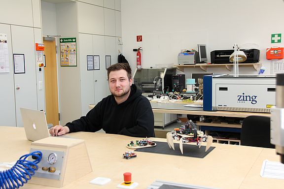 In der Werkstatt Physical Computing Student am Notebook, Adruino und 3D-Drucker neben ihm