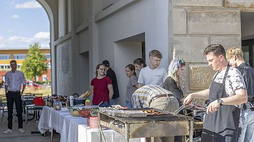 Menschen stehen am Grill